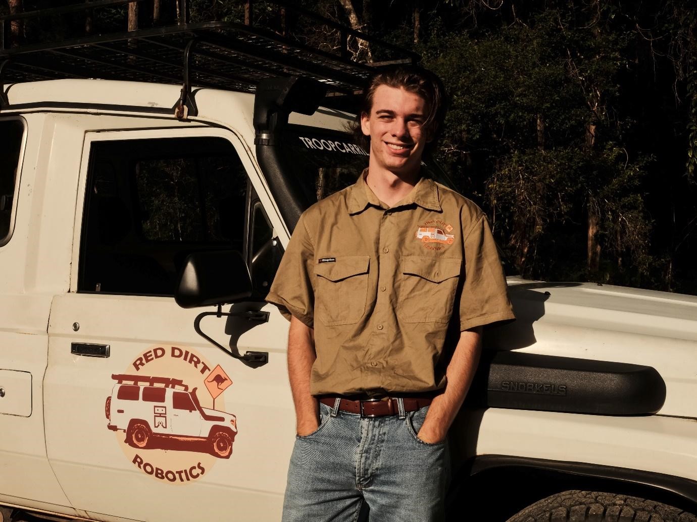 Young man standing in front of a vehicle