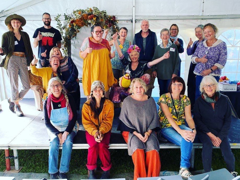 Group of people stand and sit on a stage.