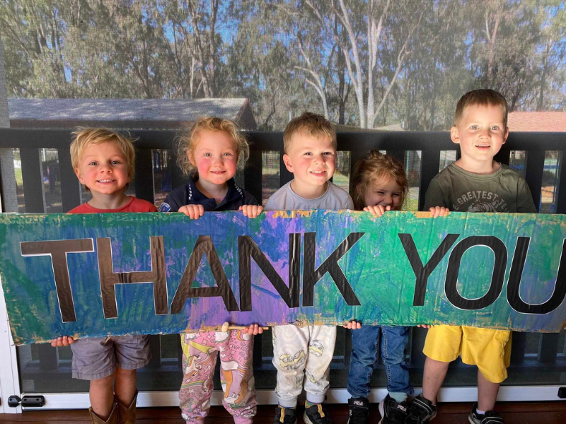Children holding a sign that says Thank You.
