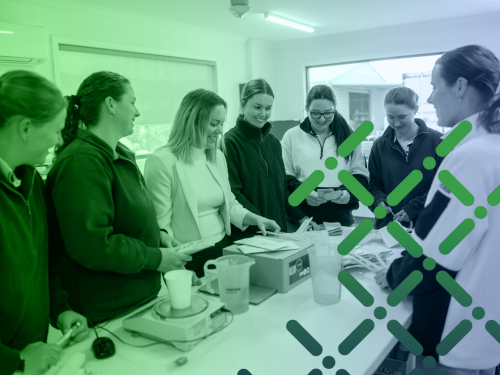 A group of women standing around a table talking and laughing together.