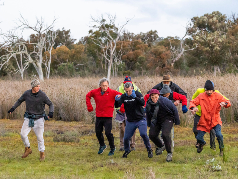 A group of men are captured jumping as they dance in a field.