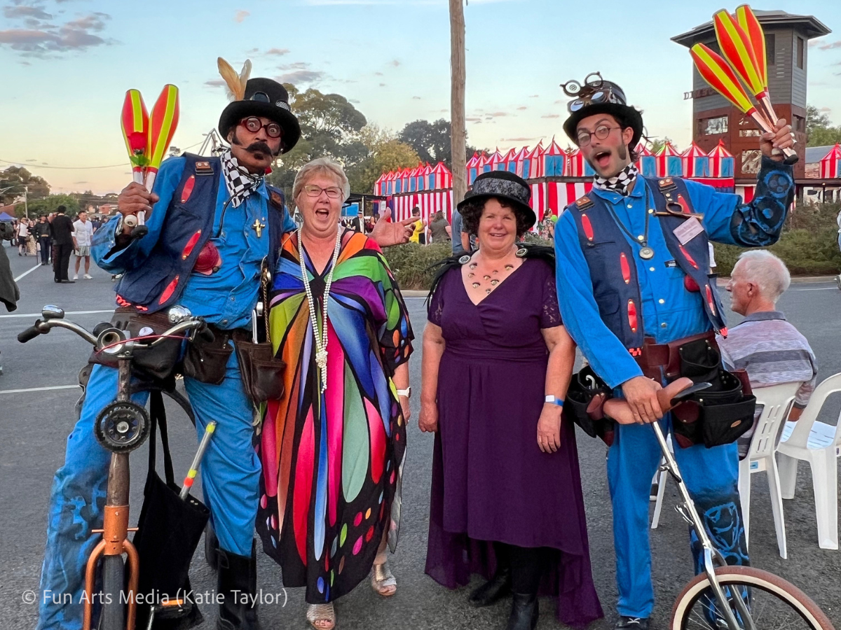 Four people stand in fancy dress at a festival. 