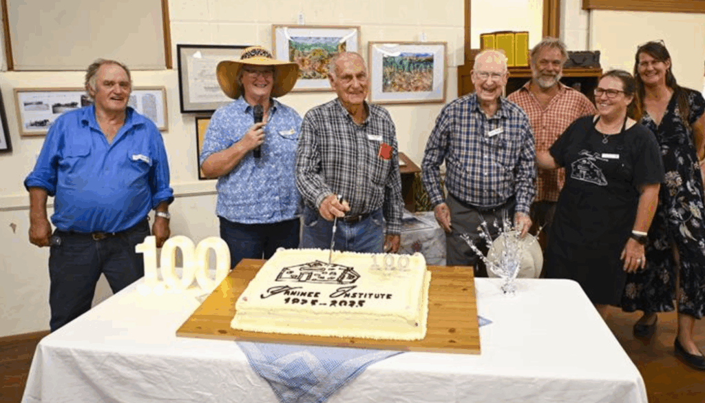 Yaninee Institute celebrated it's 100th anniversary with a cake. There are people standing behind the table looking happy.