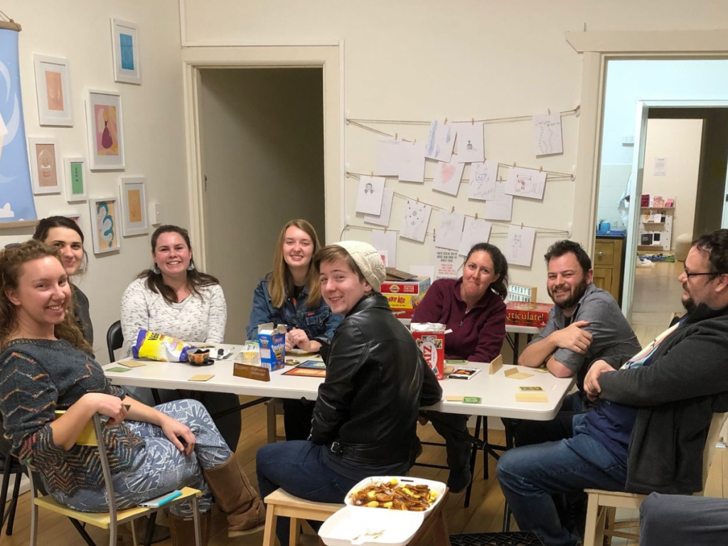HEADING: Riverland Skillin’ It inspires and empowers young people. IMAGE: Eight people sitting arounda table facing the camera.