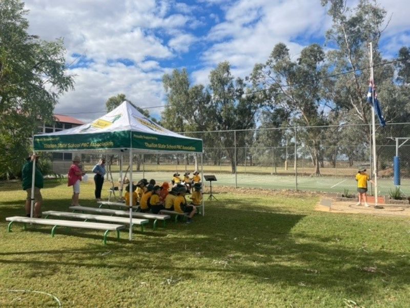 Group of students and teachers sitting under a new shade structure.