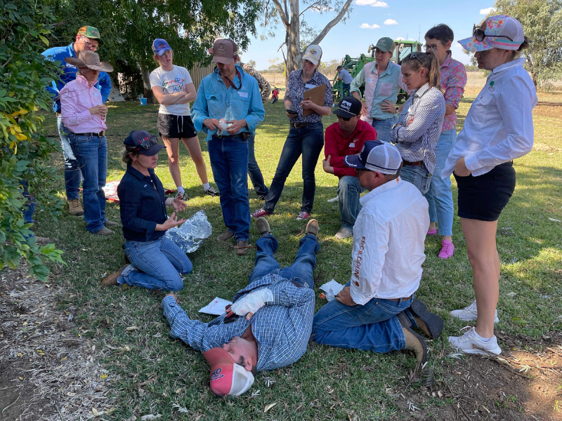 Group of people gathered in a mock first aid scenario outdoors.