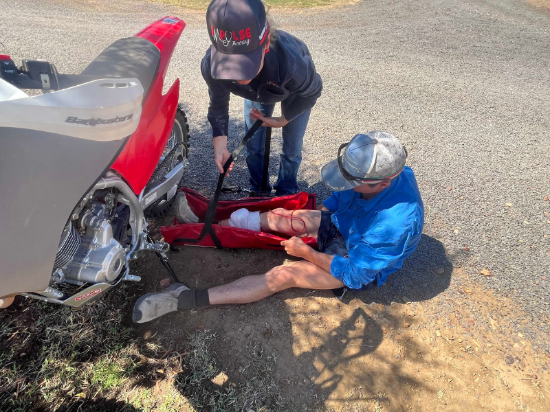 Group of people gathered in a mock first aid scenario outdoors next to a motorised vehicle. 