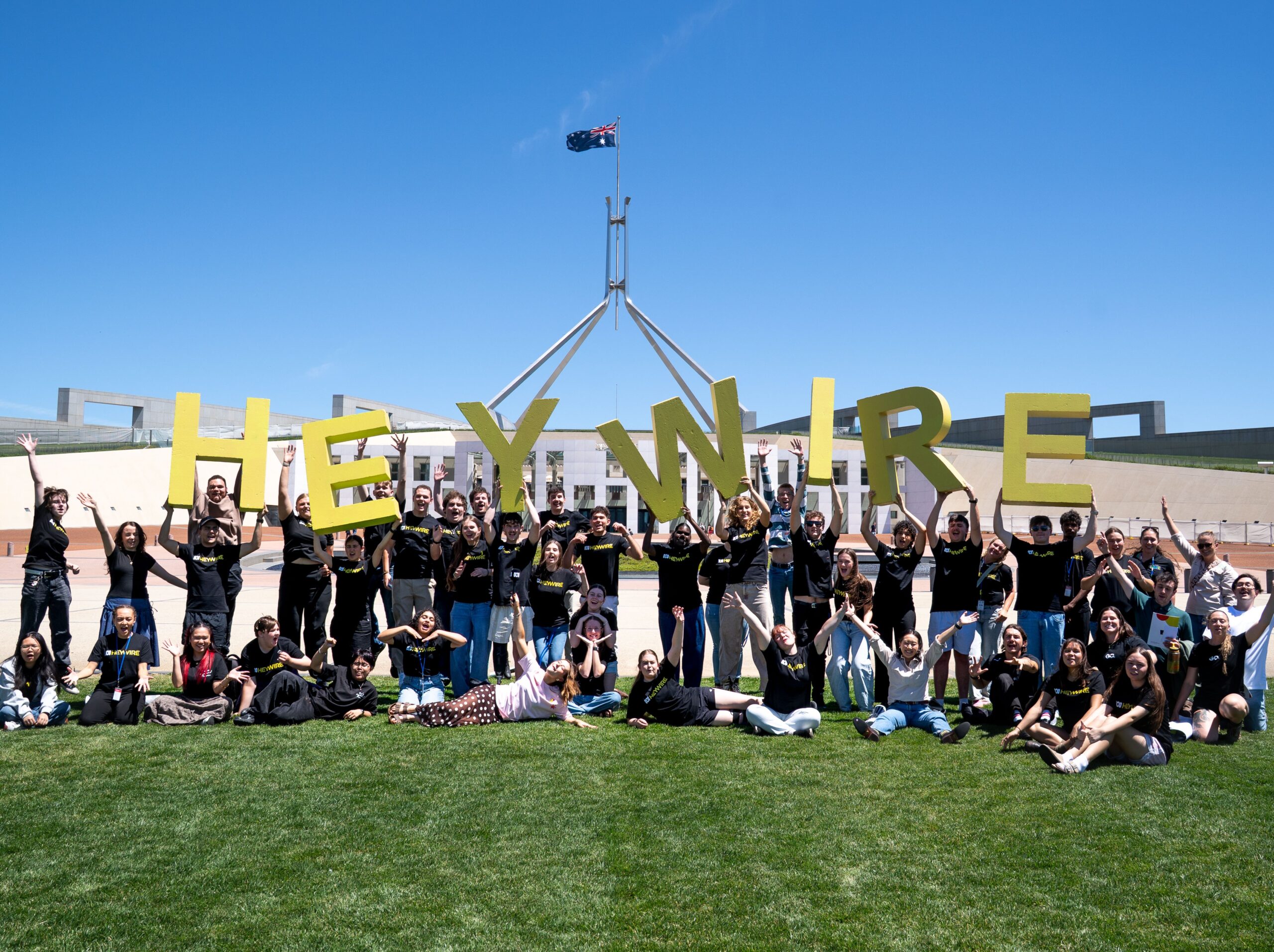 Group of young people holding up letters that spell out HEYWIRE.