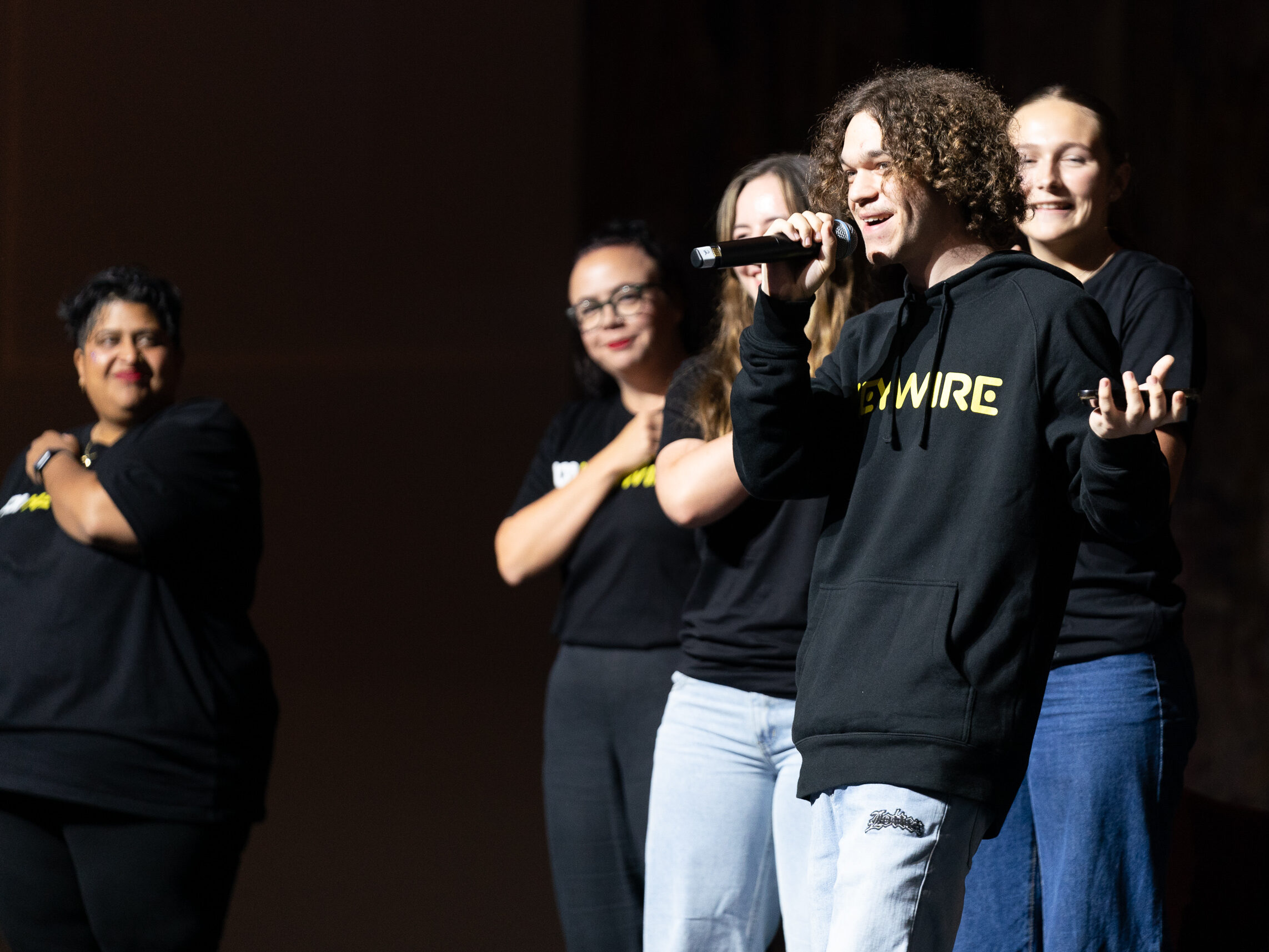 Person speaking into microphone with other people in background.