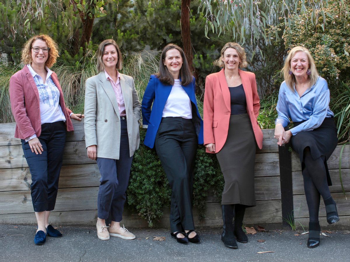 Five women standing in front of a garden