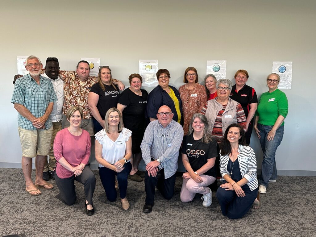 A group of people, with the front row kneeling down on the ground and others standing behind them.
