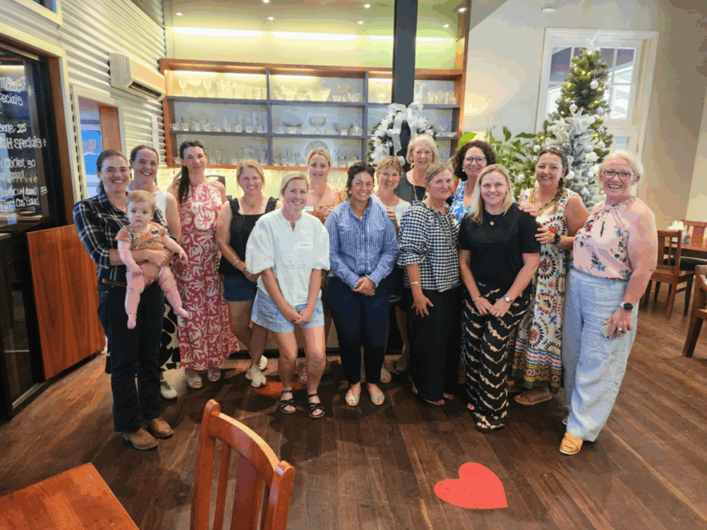A large group of women stand and pose in a lobby for a photo. 