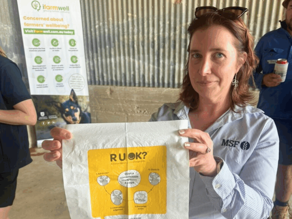 A woman holds up a tissue with the R U OK? logo printed onto it. 