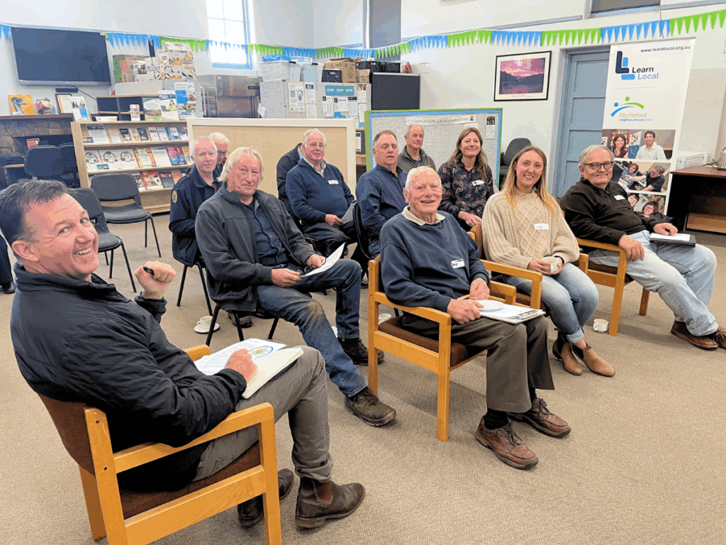 Group of people are seated in a room for a workshop / meeting. 