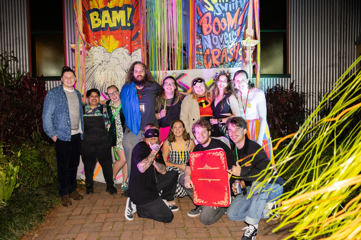 A group of people in superhero costumes in front of some comic posters.