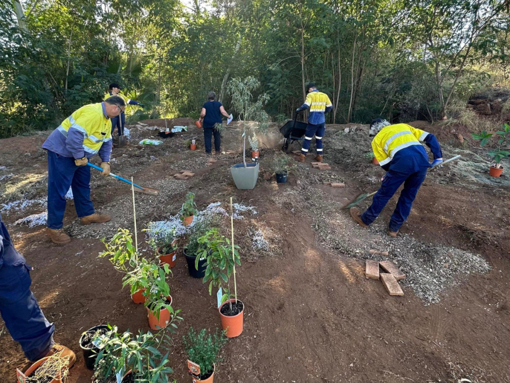 People using gardening tools to cultivate a garden.