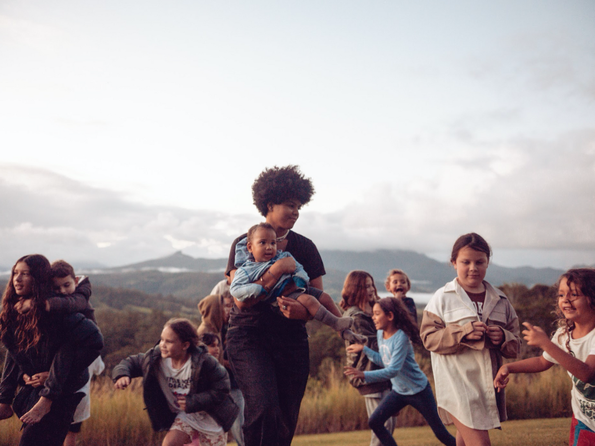 A group of young girls are playing and running in a rural landscape outdoors. 