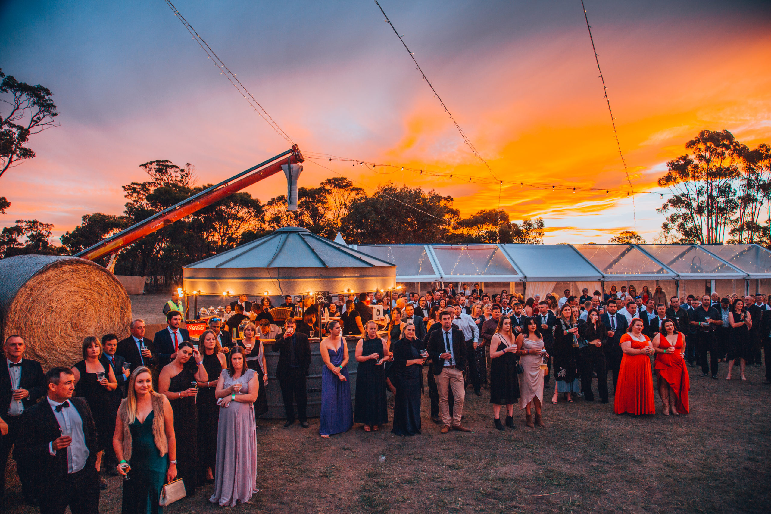 Attendees to the Dancing in the Dirt ball standing in front of a lit up marquee watching a presentation