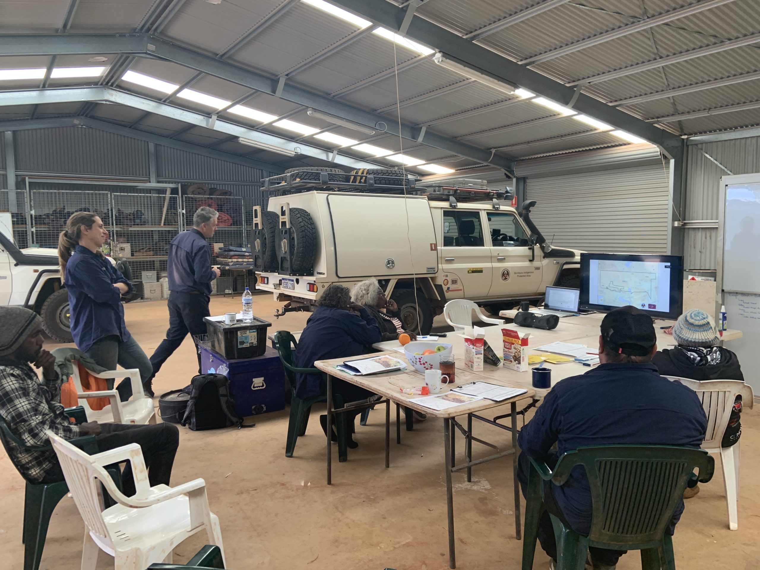 Indigenous Rangers sit in a shed watching a computer screen