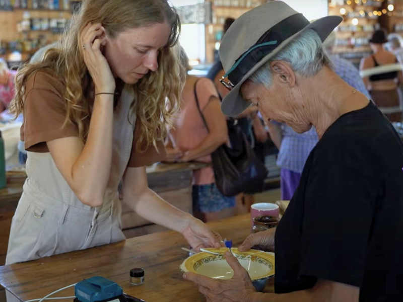 Two women working together to repair a broken bowl.