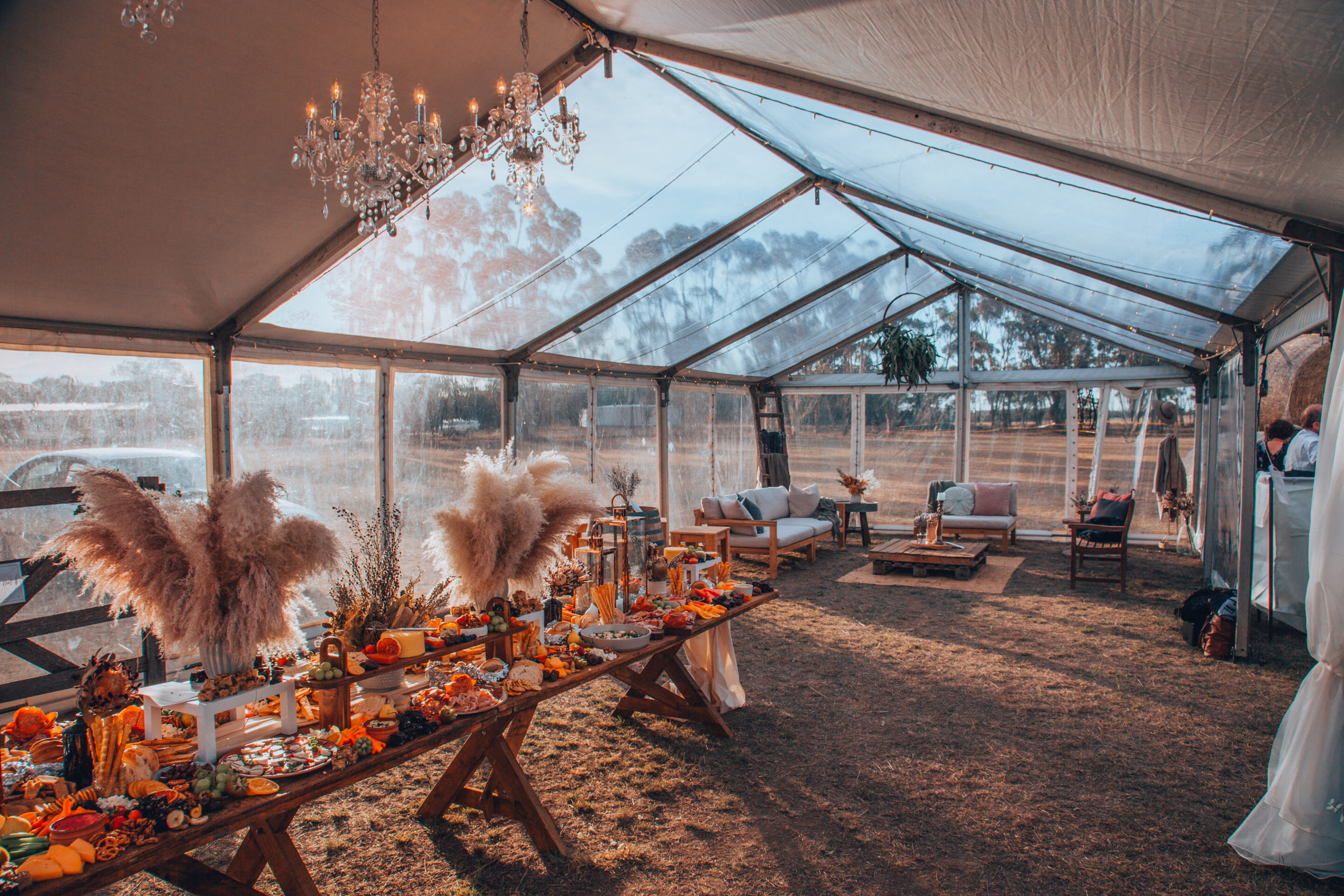 The marquee at the Dancing in the Dirt ball set up ready for guests, with a table spread with food and chandeliers hanging
