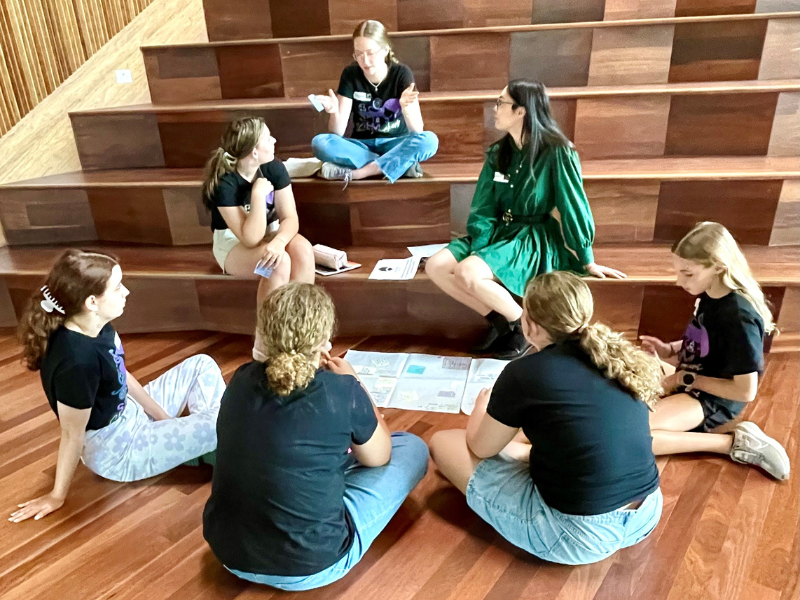 Group of girls sitting across different levels on stairs.