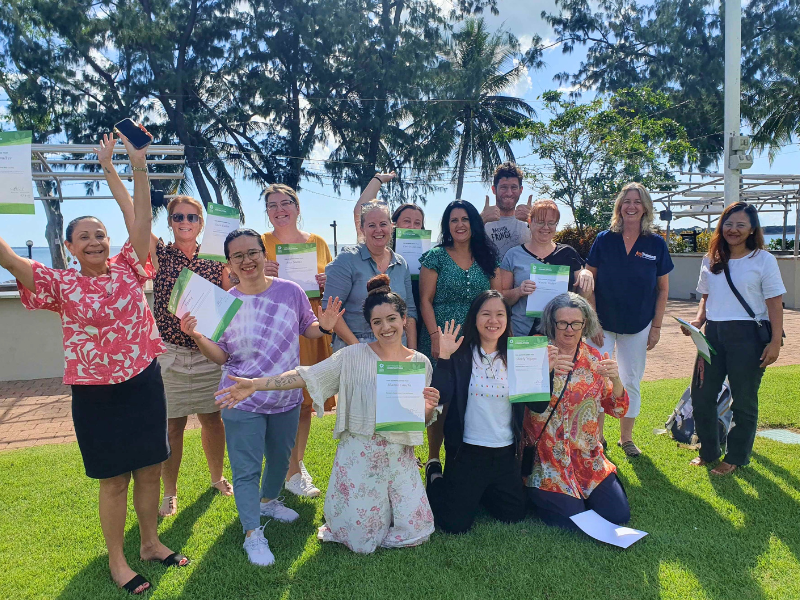Group of people celebrating with certificates outdoors.