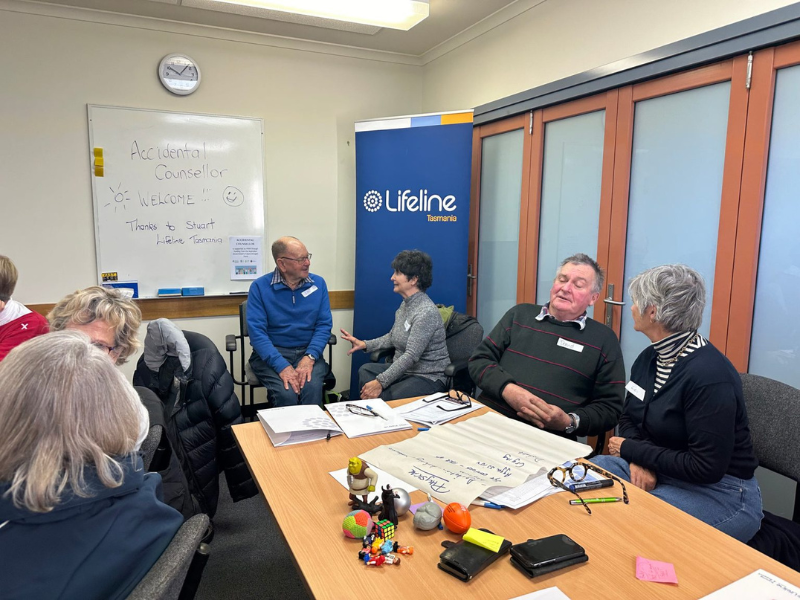 Group of people are sitting at desks talking. 
