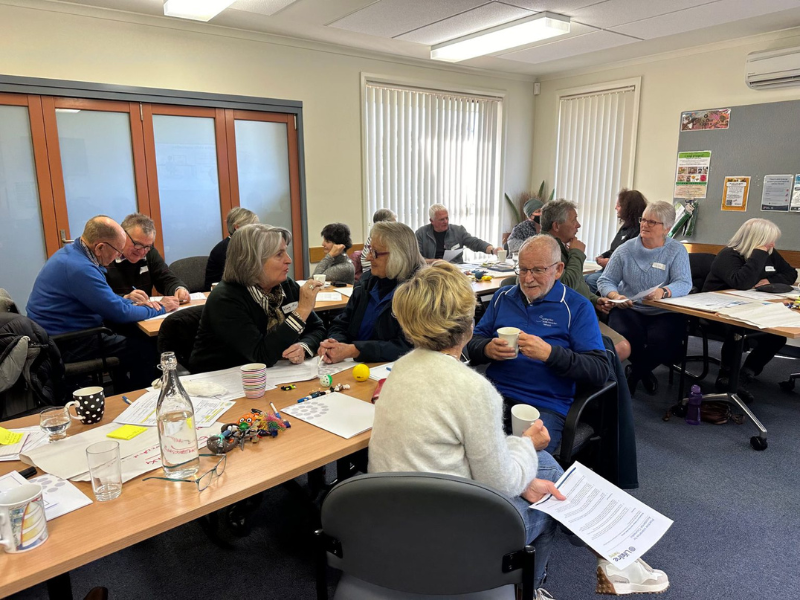 Group of people are sitting at desks talking. 