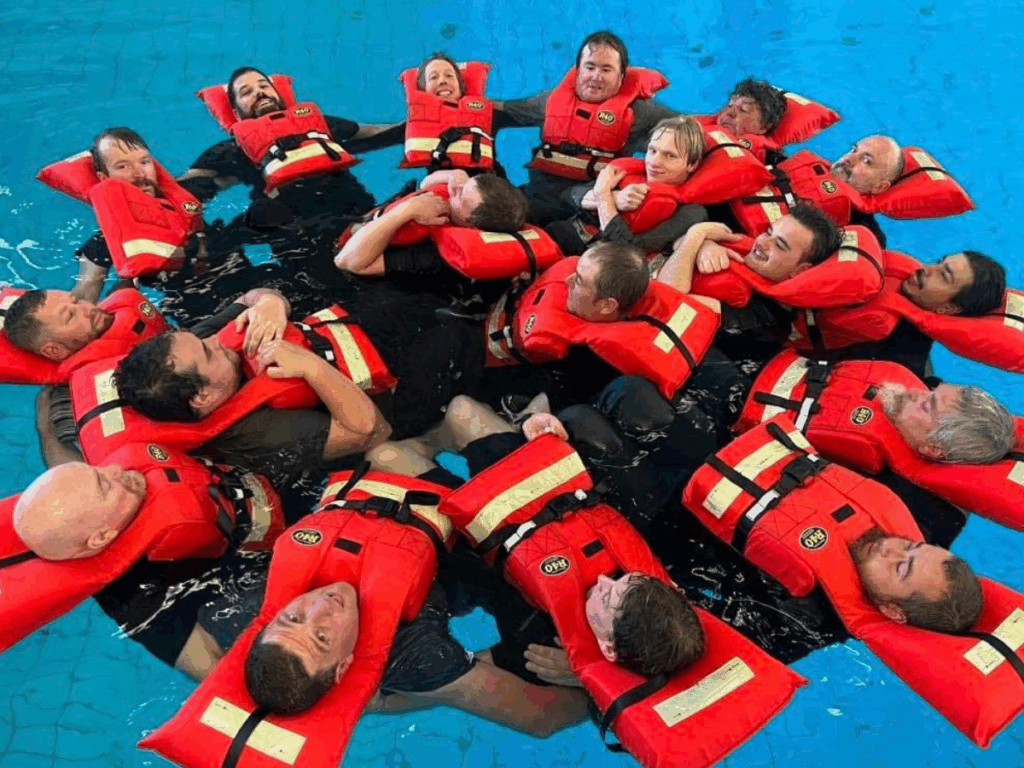 A group of people wearing red life jackets floating in a circle in a pool.