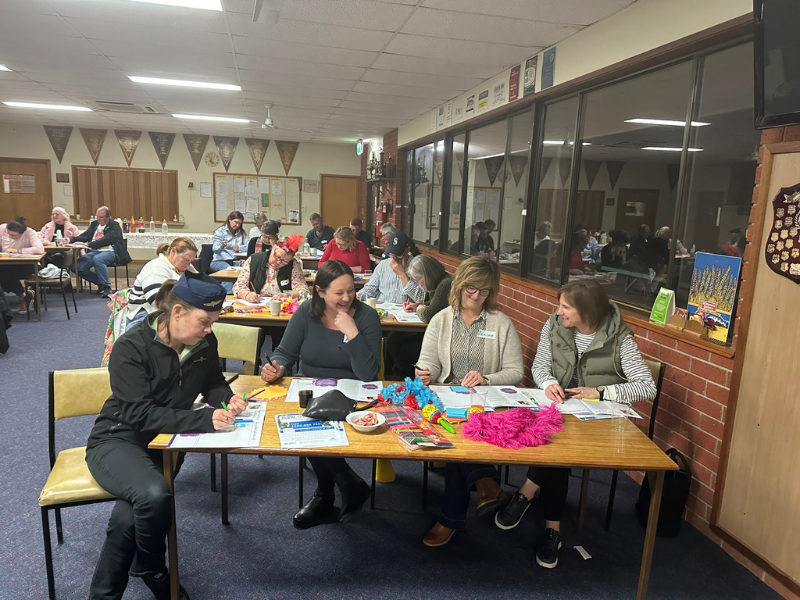 Four women sit at a desk in a classroom. 