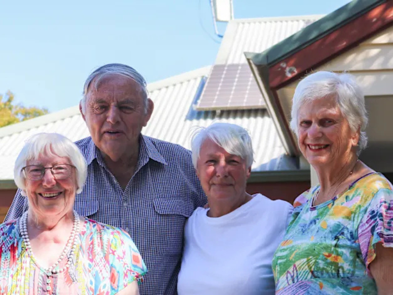 Four seniors pose for a photo in white and floral tops. 