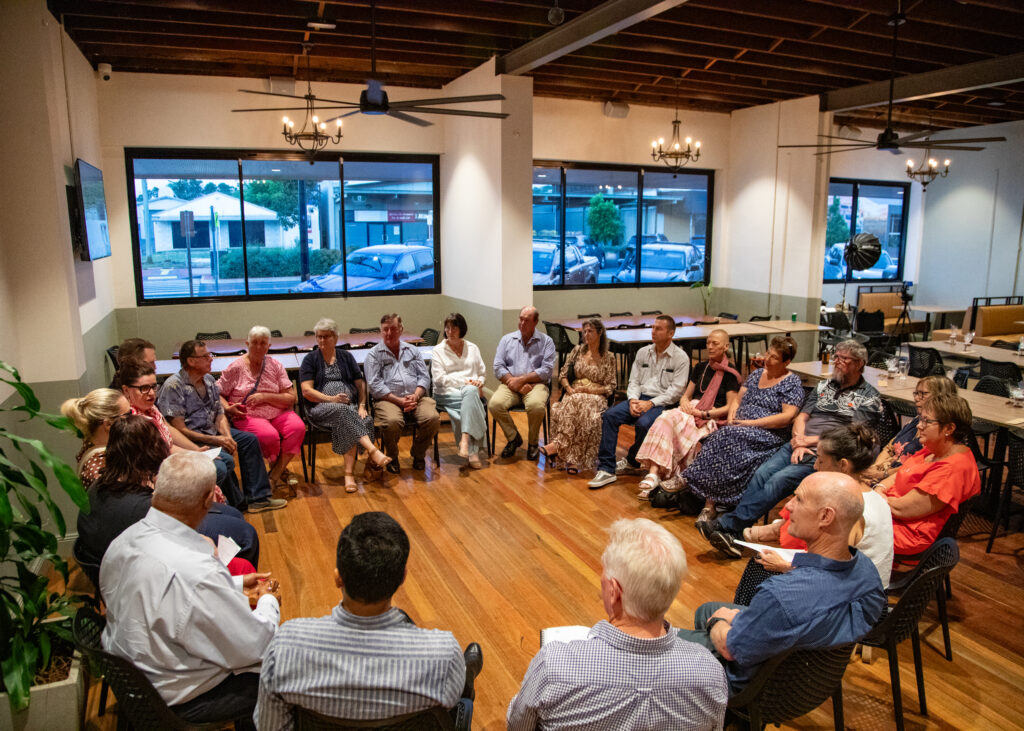 People sitting in a circle with windows in the background.