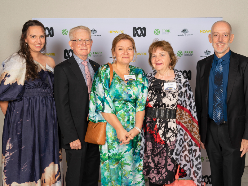 Group of people standing in front of a media board.