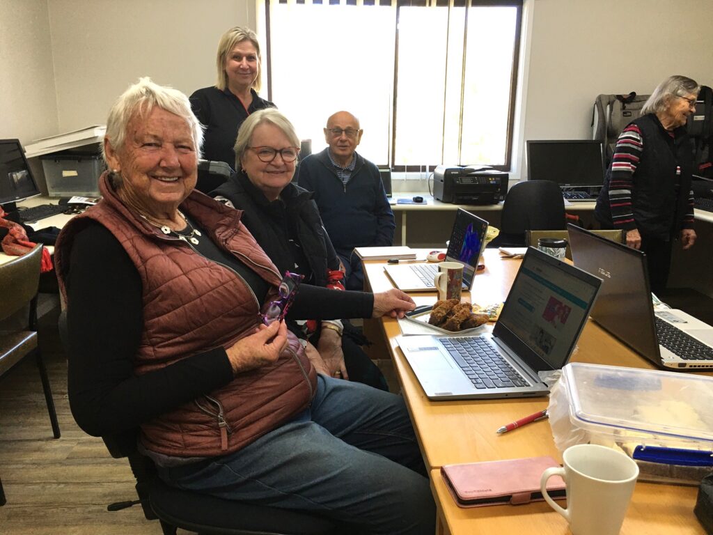 Older people sitting at a desk with a computer on it.